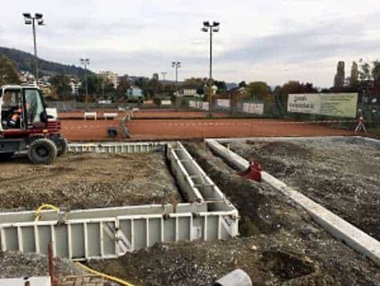 Construction site showing the foundation work for a padel court with machinery and materials.