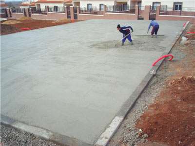 Two workers finishing a concrete surface on a construction site.